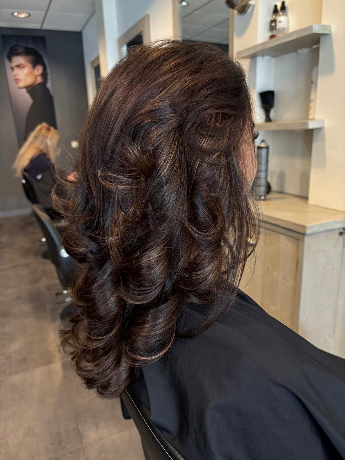 Donkerbruine krullen in de salon, met de kappersstoel op de achtergrond