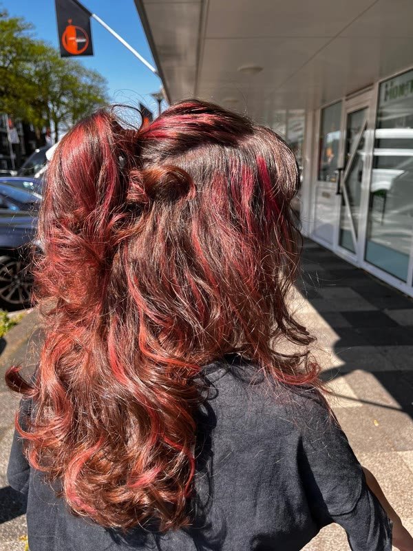 Koperrode balayage met volle krullen, buiten voor de salon