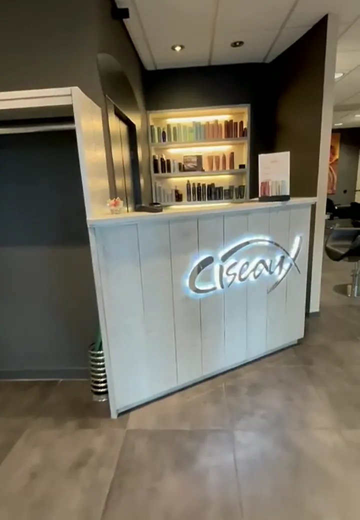 De balie met het verlichte Ciseaux-logo en de productkast