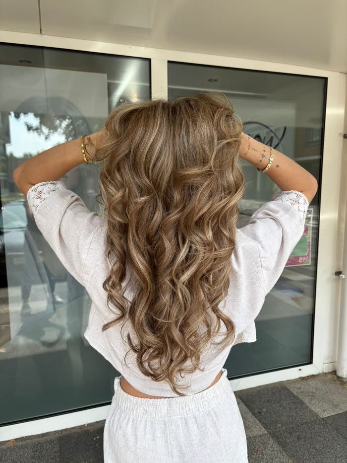 Lange bronde krullen met highlights, buiten gefotografeerd