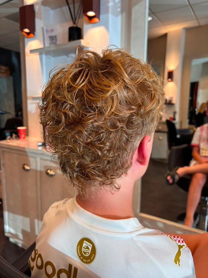 Blonde krullen na een permanent, van achteren gezien in de salon